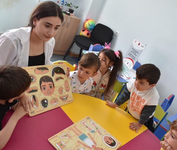 Eine Pädagogin betreut Kinder in der Caritas-Kinderbetreuung, während ihre Mütter an Weiterbildungen teilnehmen.