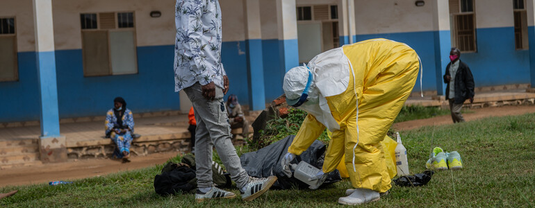 Person in Schutzanzug desinfiziert Ausrüstung vor Klinik in der DR Kongo während eines Ebola-Ausbruchs.