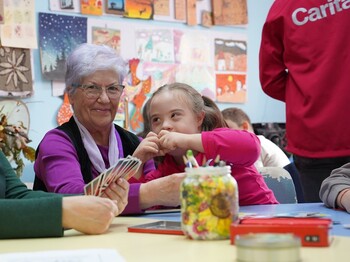 Eine freiwillige Mitarbeiterin spielt mit einem Kind UNO