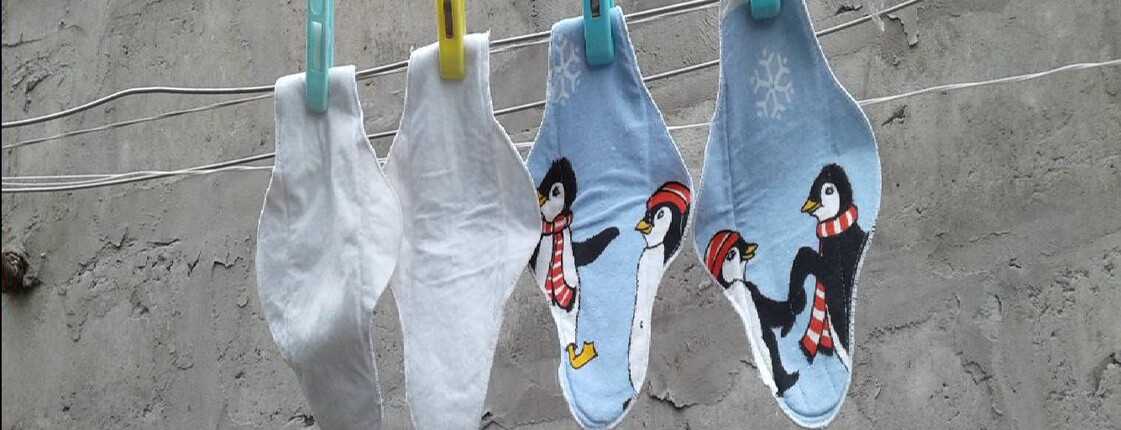 vier Stoffbinden hängen an einer Wäscheleine. Zwei sind weiß, zwei haben Pinguinmotive.