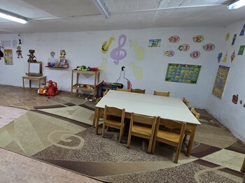 Ein Schutzraum mit Tisch und Sesseln, an den Wänden sind Kinderzeichnungen zu sehen.