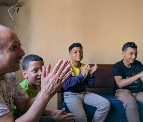 Durch Sing- und Klatschspiele wird das seelische Wohlbefinden der Kinder gefördert.  Ein Mann und vier Kinder klatschen und haben Spaß.