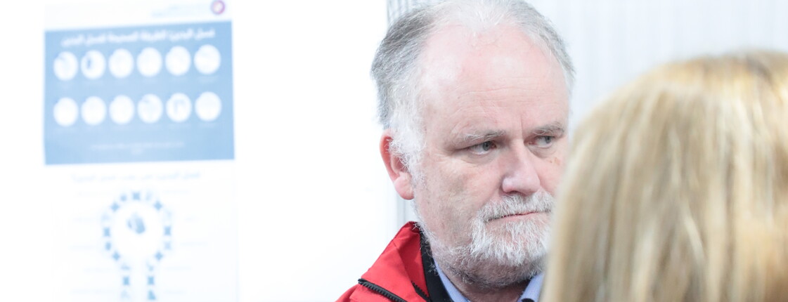 Andreas Knapp mit roter Caritas-Jacke vertieft in ein Gespräch