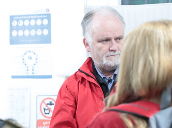 Andreas Knapp mit roter Caritas-Jacke vertieft in ein Gespräch