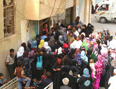 Eine Menschenmenge stellt sich bei einem Eingang an