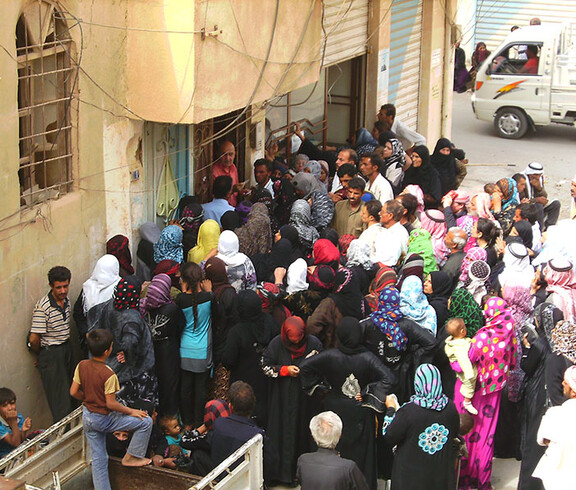 Eine Menschenmenge stellt sich bei einem Eingang an