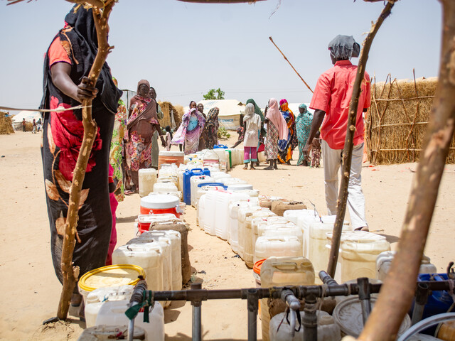 Menschen stellen sich an für Kanister mit sauberem Wasser. 