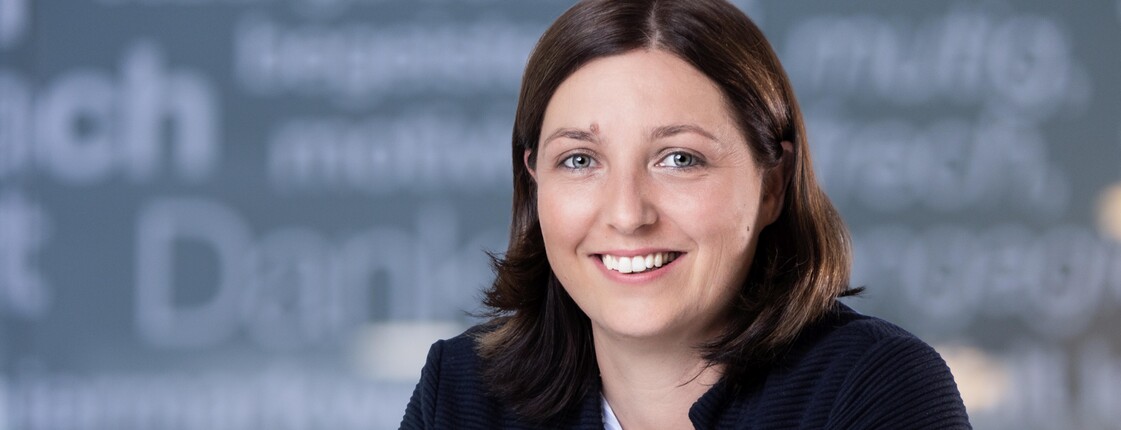 Porträtfoto von Nora Tödtling-Musenbichler vor einem Hintergrund mit Schriftzügen, aufgenommen von Jorj Konstantinov