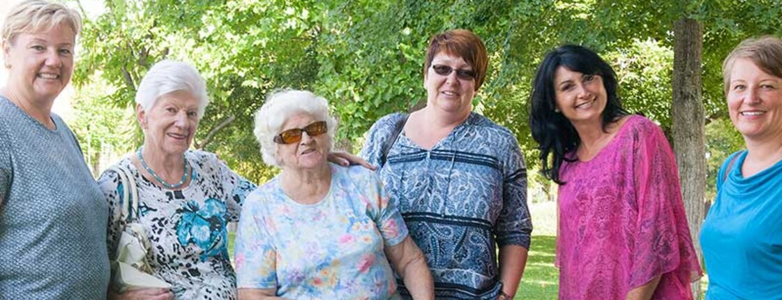 Mehrere Frauen stehen gemeinsam im Freien und lächeln in die Kamera.