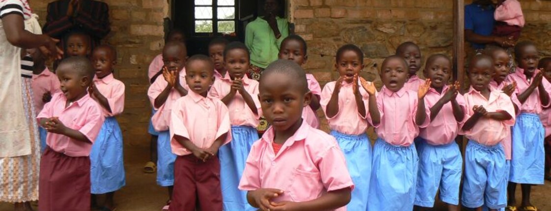 Eine Gruppe von Schulkindern in Schuluniform steht vor einem Gebäude und klatscht gemeinsam.