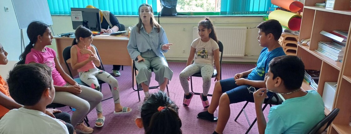 Kinder und eine erwachsene Person sitzen im Sesselkreis und reden