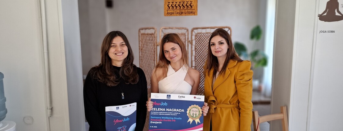 Drei Frauen stehen nebeneinander in einem Raum und halten ein Zertifikat sowie eine Mappe in den Händen.