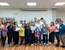 Eine große Gruppe von Menschen steht in einem Raum zusammen und hält Zertifikate in die Kamera.