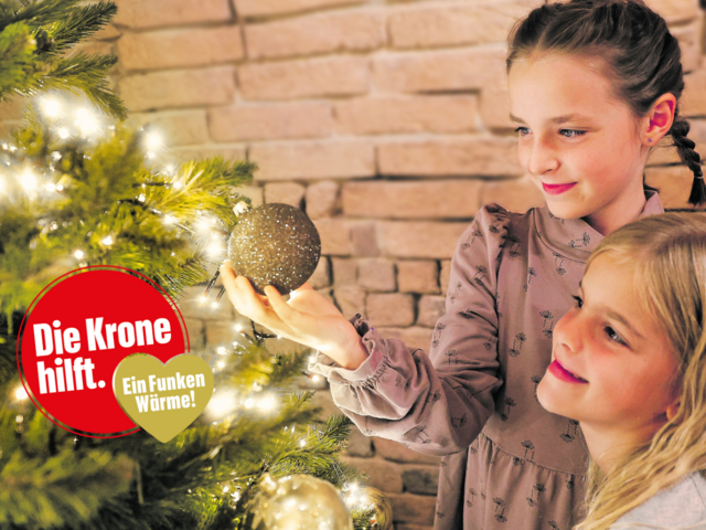 Zwei Mädchen beim Christbaum - und ein Logo "Die Krone hilft. Ein Funken Wärme"