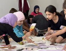 Kinder malen gemeinsam auf großen Papierbögen im Rahmen eines kreativen Workshops im Libanon