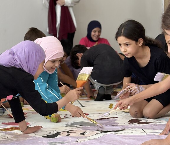 Kinder malen gemeinsam auf großen Papierbögen im Rahmen eines kreativen Workshops im Libanon