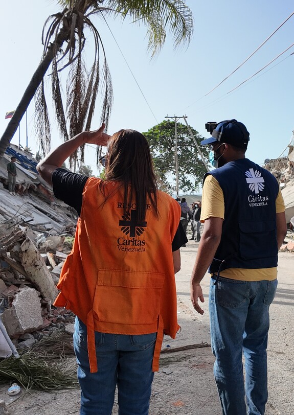 Caritas-Helfer*innen stehen zwischen Trümmern nach dem Erdbeben in La Guaira.