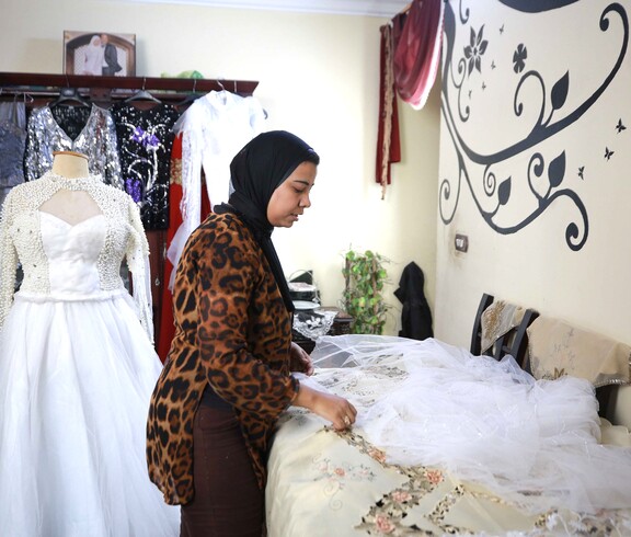 Eine Frau näht bestickt Hochzeitskleider.