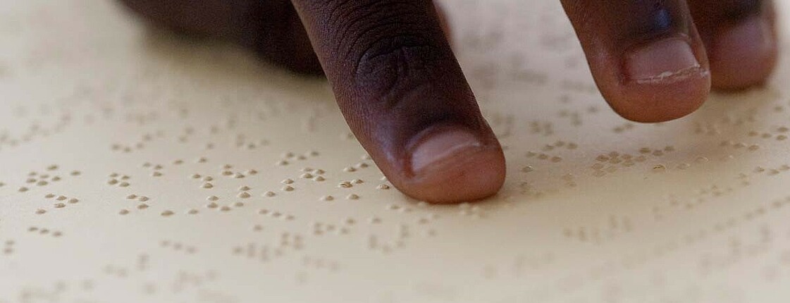 Das Bild zeigt Finger auf einer Oberfläche mit Brailleschrift