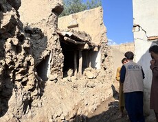 Übergangswege durch zerstörte Häuser, davor drei Personen mit dem Rücken zum Betrachter