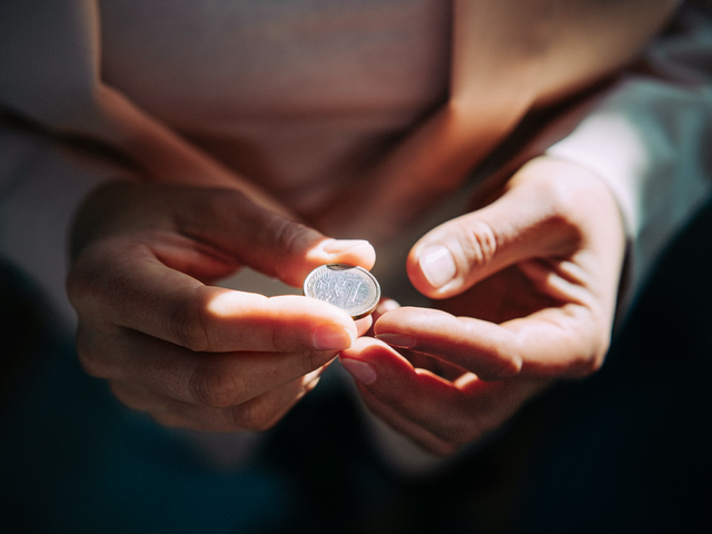 Zwei Hände halten einen Euro in der Hand.