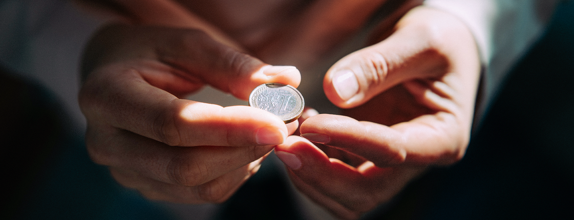 Hilfe für Menschen in Not Zwei Hände halten einen Euro in der Hand.