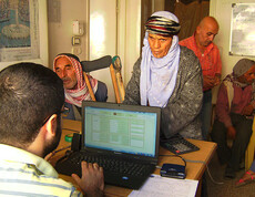 Ein Mann arbeitet am Computer, 3 Männer stehen davor