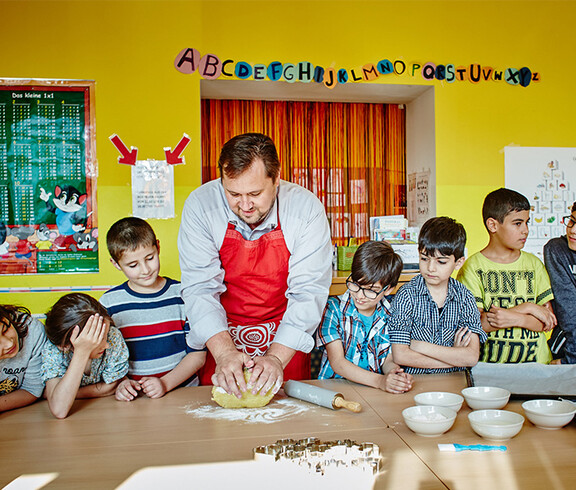 Caritasdirektor Hannes Zieselsberger mit einer Gruppe von Kindern beim Keksebacken