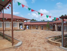 Blick auf Gebäude und Innenhof der neu eröffneten Ausbildungsstätte mit feierlichen burundischen Fahnen 