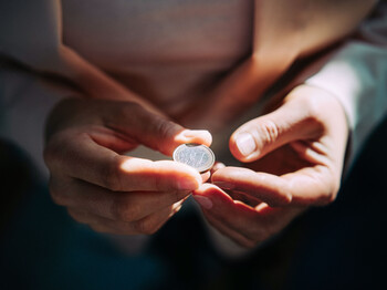 Zwei Hände halten eine Ein-Euro-Münze.