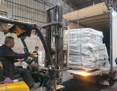 Ein Gabelstapler lädt palettierte Hilfspakete in einen Lkw für die Verteilung.