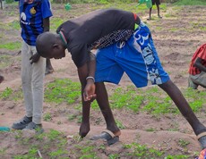 ein südsudanesischer Bursche jätet ein kleines Beet. 