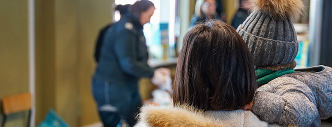 Ukraine-Krieg: Eine Frau mit Kind am Grenzübergang nach Polen, im Hintergrund ist eine Essensausgabe