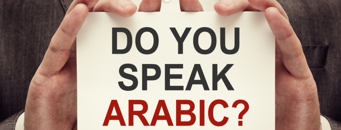Person hält ein Schild auf dem steht: "Do you speak Arabic?"?