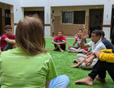 Das Straßenkinderzentrum geht auch auf die emotionalen Bedürfnisse der Kinder ein.  Eine Gruppe Kinder und eine Betreuerin sitzen auf einem Fußballrasen