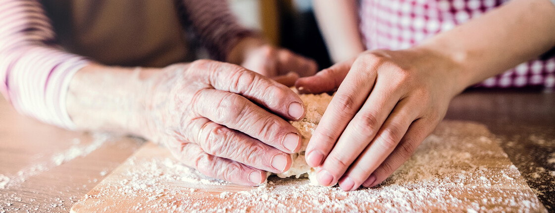 An elderly grandmother with an adult granddaughter at home, baking.