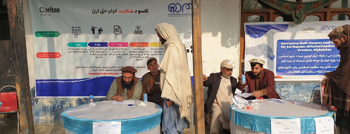 Männer erhalten in einem Caritas-Zentrum finanzielle Soforthilfe nach einem Erdbeben in der Provinz Khost, Afghanistan
