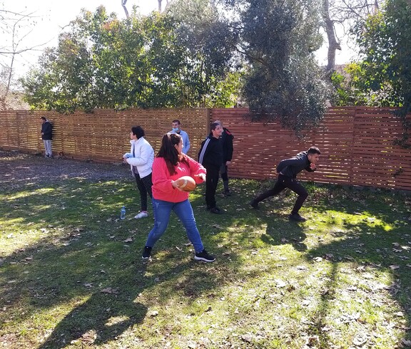 Mehrere Personen spielen gemeinsam mit einem Ball im Freien auf einer Wiese.