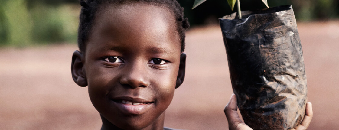 Ein Mädchen hält stolz einen kleinen Setzling in den Händen