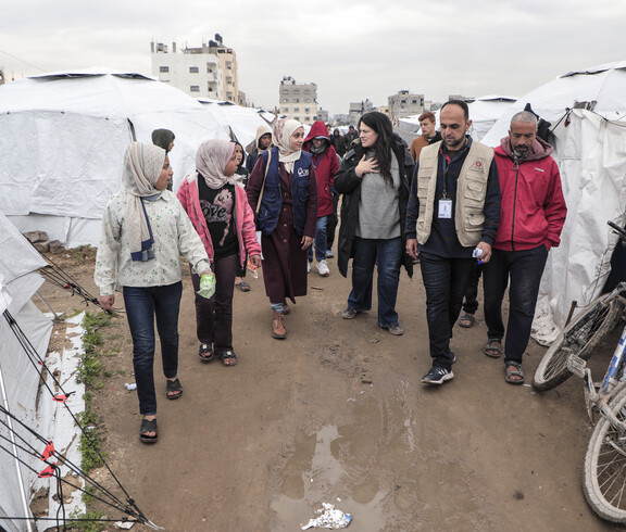 Eine Gruppe von Menschen, darunter Kinder, steht zwischen Zelten im Camp.