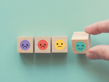 Hand choosing happy smile face wooden block, good feedback rating and positive customer review, mental health assessment, child wellness,world mental health day, think positive, compliment day concept Hand choosing happy smile face wooden block, good feedback rating and positive customer review, mental health assessment, child wellness,world mental health day, think positive, compliment day concept