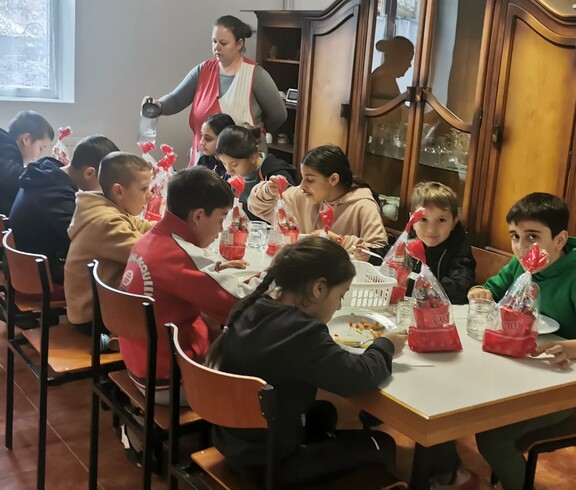 Eine Gruppe Kinder sitzt an einem Tisch und isst. Der Tisch ist mit Nikolausdekorationen geschmückt. 