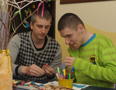 Ein Betreuer arbeitet mit einem Kind, das eine Beeinträchtigung hat, und hilft ihm bei einer kreativen Aktivität im Kinderdorf Gomel.