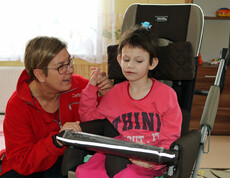 Eine Betreuerin unterstützt ein Kind im Kinderdorf Gomel bei einer therapeutischen Übung und sorgt für eine liebevolle Betreuung.