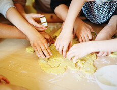 Kinder stechen Kekse aus einem Teig aus
