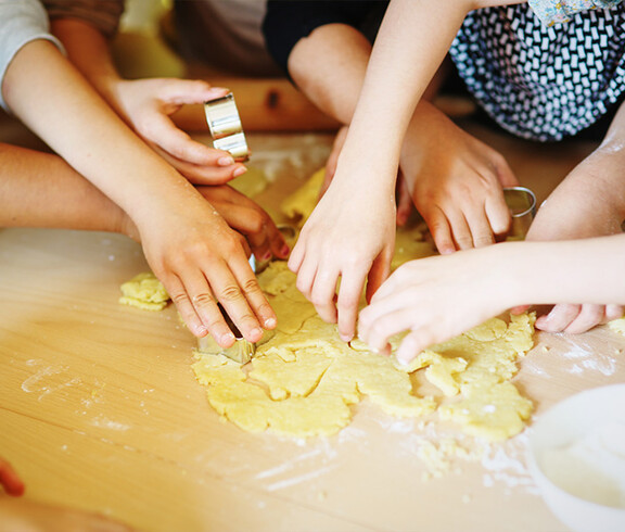 Kinder stechen Kekse aus einem Teig aus