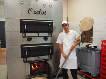Foto: KIZ/lila Ein junger Mann mit Brotschieber rechts vor einem großen Backofen stehend