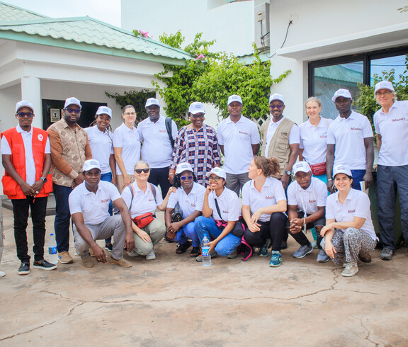 Eine Gruppe von Menschen steht und sitzt gemeinsam für ein Gruppenfoto vor einem Gebäude.