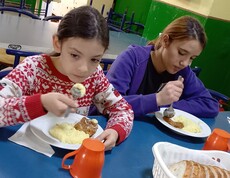 Zwei Mädchen sitzen am Tisch und essen. 