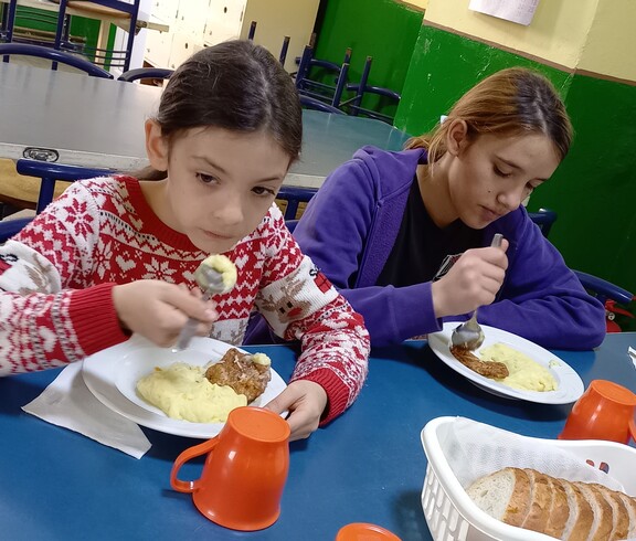 Zwei Mädchen sitzen am Tisch und essen. 